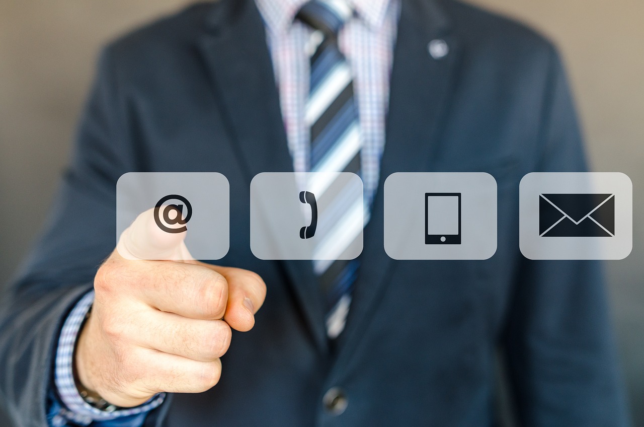 Man is a suit pointing at phone, message, and communication icons.