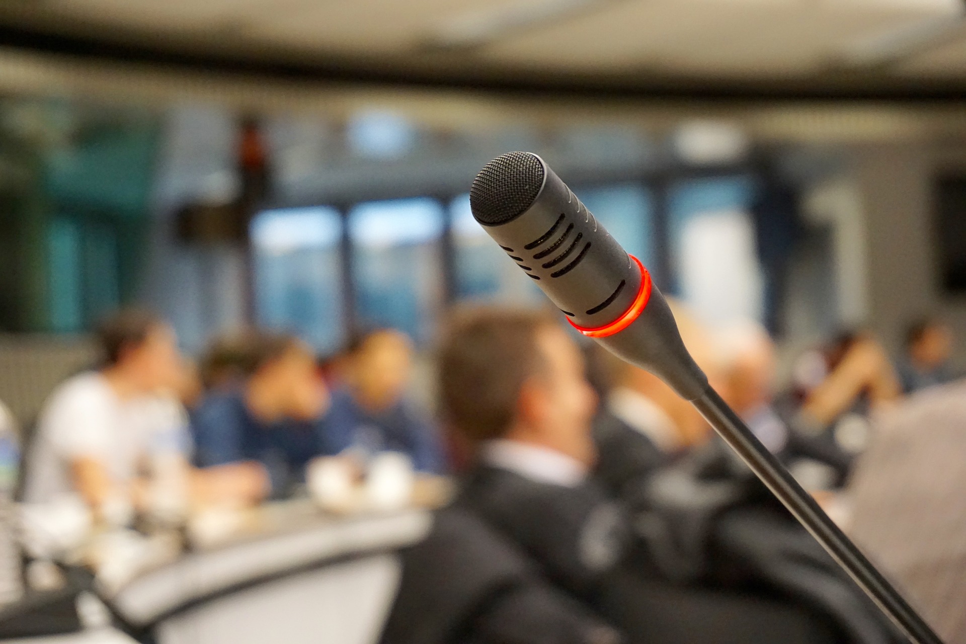A microphone in the foreground, and a well-attended class of law students in the background.