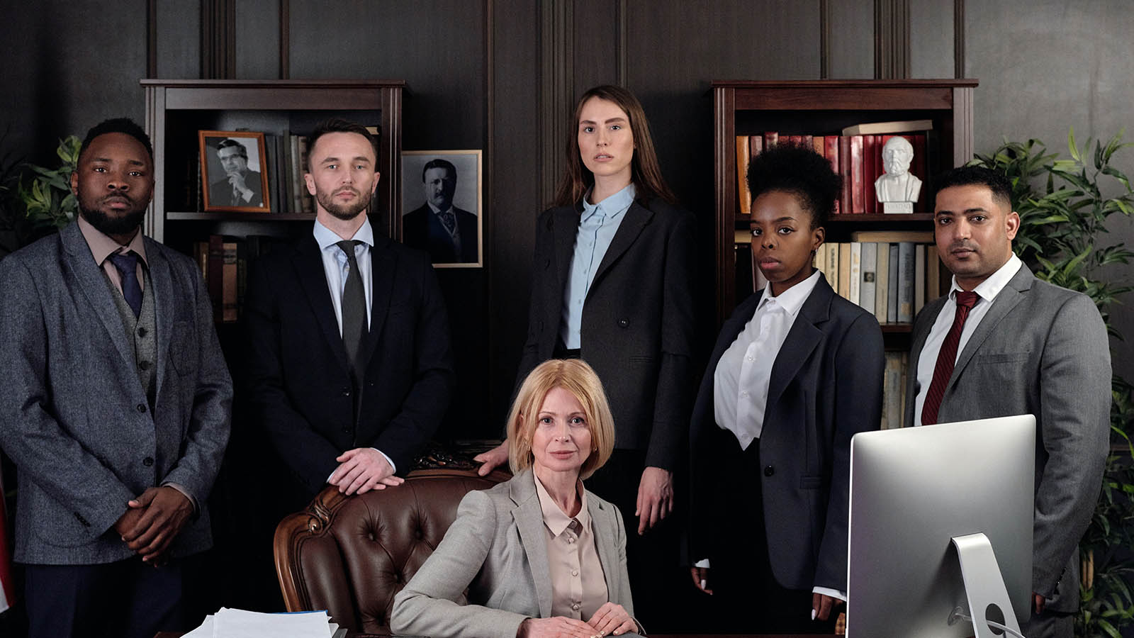 Male and female legal professionals pose for a group photo in a law office.